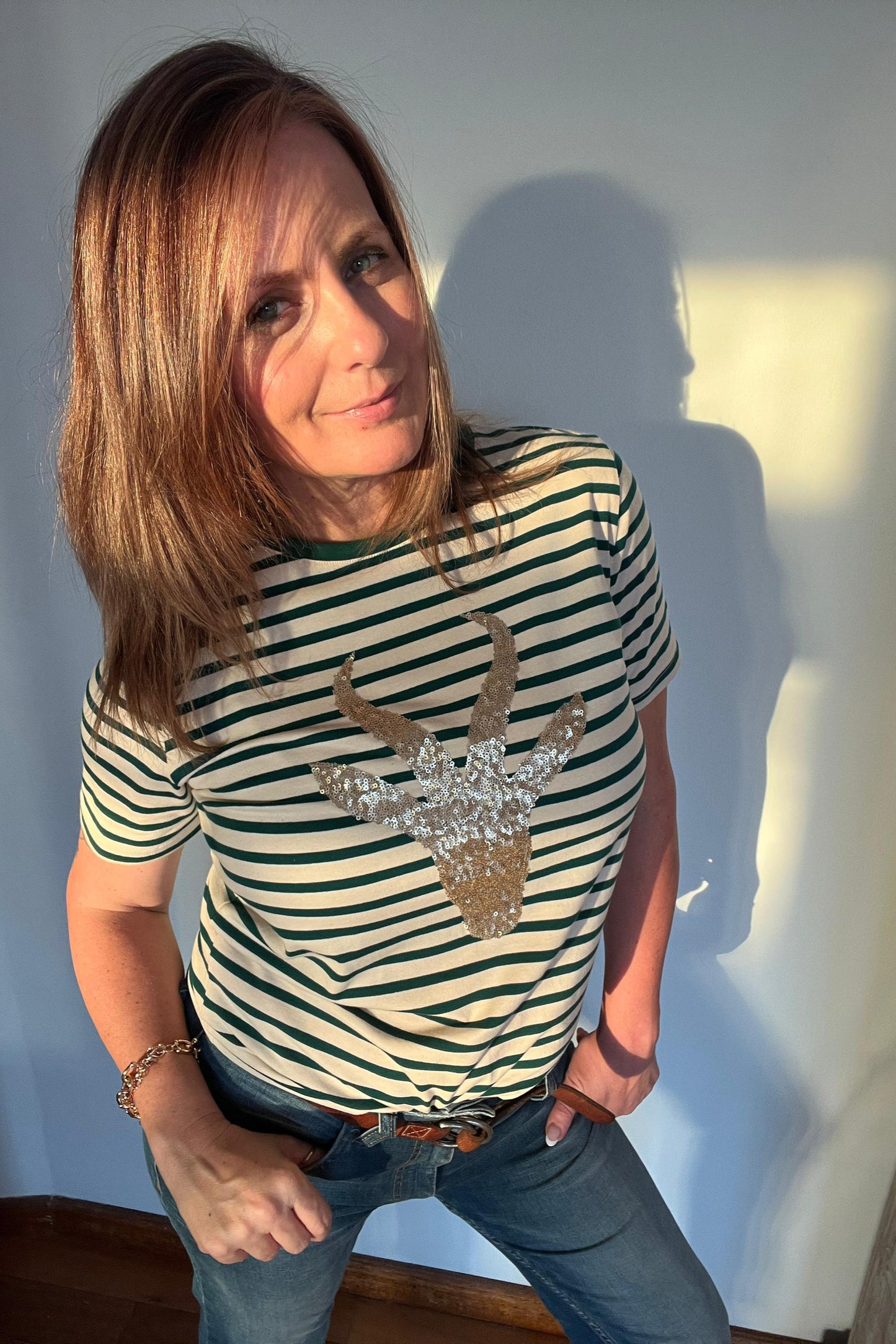 woman wearing striped t shirt with sequined springbok design in green and gold