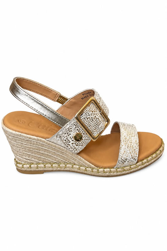 Elegant gold snake glitter wedge sandals featuring sparkling rhinestone embellishments, a statement square buckle with gold trim, a comfortable tan footbed, and an adjustable slingback strap. Perfect for adding glamour to any outfit.