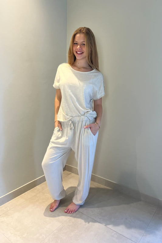 Smiling woman wearing a relaxed-fit white short-sleeve top with a round neckline, paired with light-wash blue jeans for a casual, effortless everyday look.